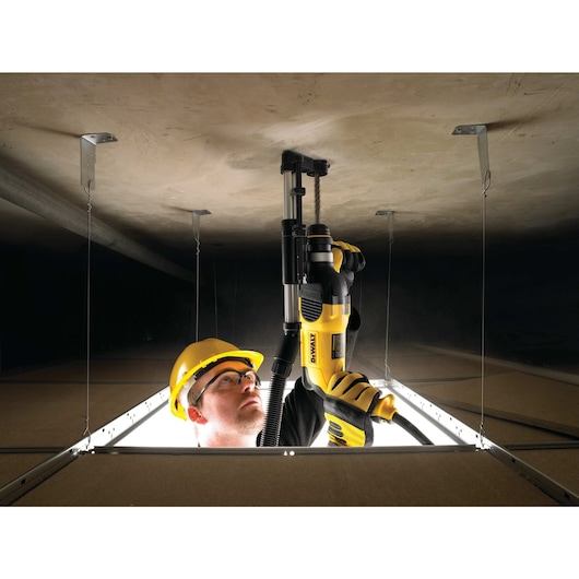 Rotary hammer with dust extractor telescope being used by person