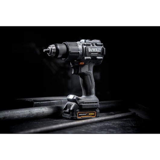 Limited Edition DEWALT/McLaren Drill Driver 3/4 right view in staged black background on black surface with LED light on