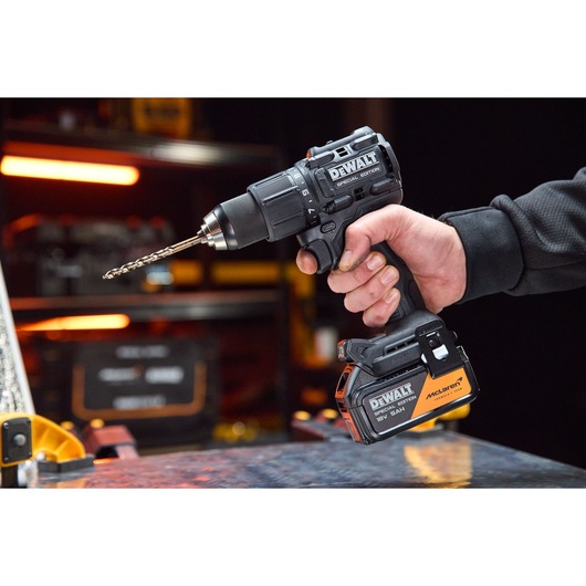 A hand holds the DEWALT x McLaren F1 Team 18V XR Special Edition Hammer Drill Driver with 5Ah battery