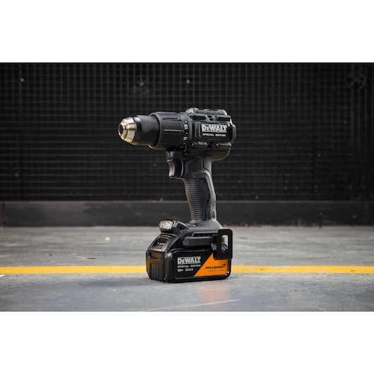 DEWALT x McLaren F1 Team 18V XR Special Edition Hammer Drill Driver with 5Ah battery standing on a concrete floor