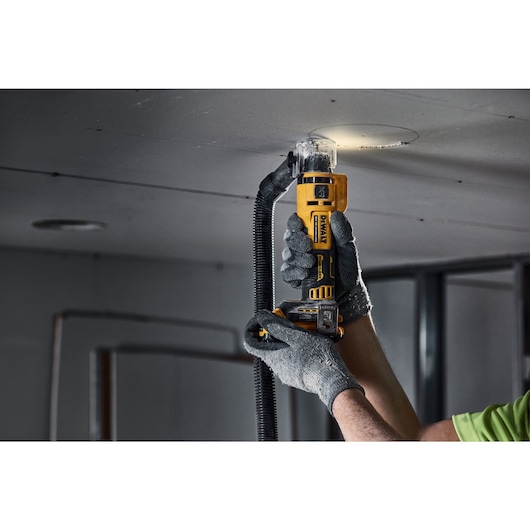 A tradesman using a DCE555 to cut a hole in drywall for a spot light