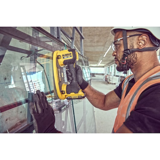 Construction worker attaches a Grabo 18V XR Suction Lifter to a pane of glass