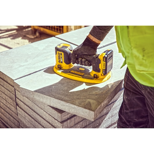 Construction worker holds a Grabo 18V XR Suction Lifter on top of a column of concrete blocks