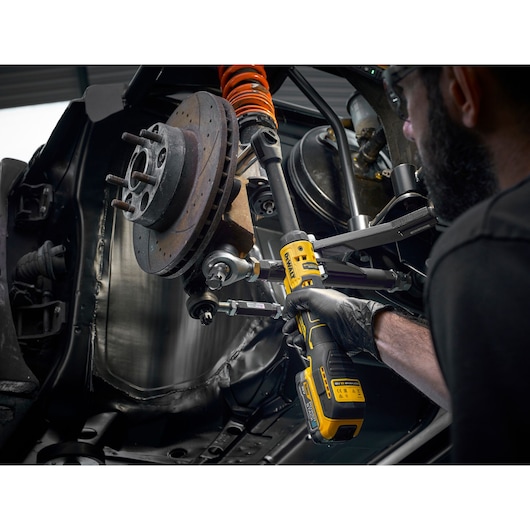 Mechanic using the DEWALT 18V XR Brushless ½” Extended Ratchet with 18V POWERSTACK battery to tighten bolts on engine