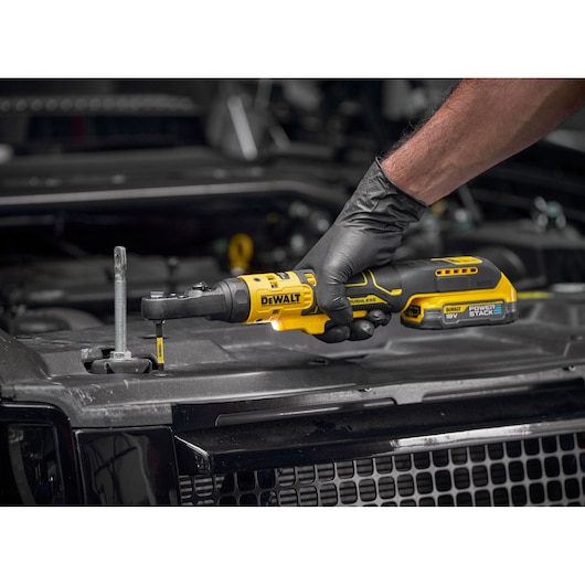 Mechanic using the DEWALT 18V XR Brushless _� , 3/8� and _� Hex Ratchet bare unit with18V POWERSTACK battery to tighten bolts on engine