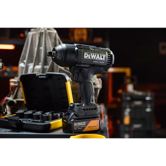 DEWALT x McLaren F1 Team 18V XR Special Edition Impact Wrench with 5Ah battery standing on a storage box alongside a socket set