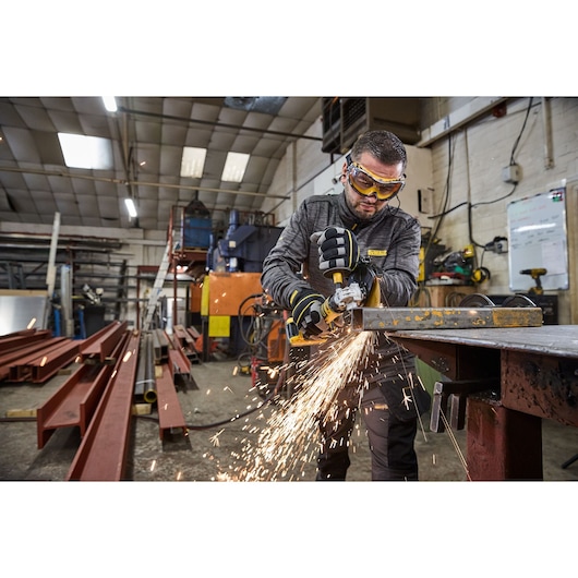Worker uses the DEWALT 18V XR Compact 125mm Angle Grinder to cut steel square tubing