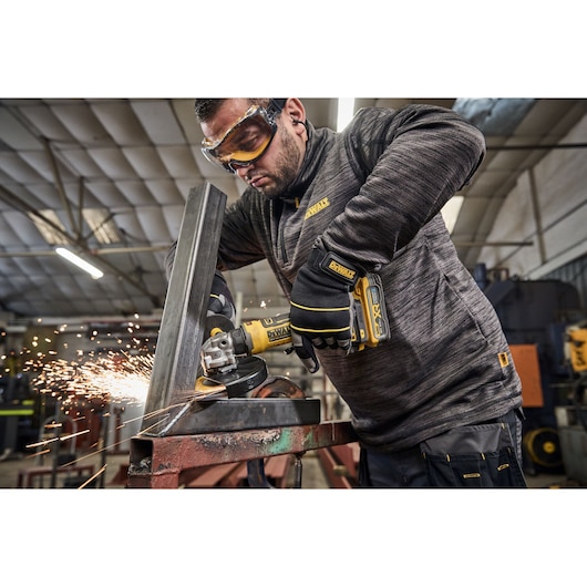 Worker uses the DEWALT 18V XR Compact 125mm Angle Grinder to grind steel square tubing