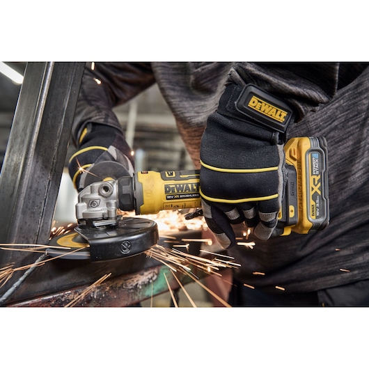 Worker uses the DEWALT 18V XR Compact 125mm Angle Grinder with 3.5ah battery to grind steel square tubing