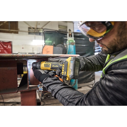 Worker uses the DEWALT 18V XR Compact Inline Grinder to smooth a metal surface