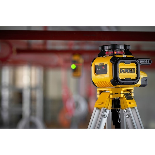 Close up of the DEWALT Alkaline Rotary Red Beam Laser on tripod on worksite in use.