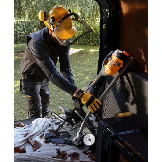A folded DEWALT 54V XR FLEXVOLT Split Boom with Edger Attachment being placed into a van 