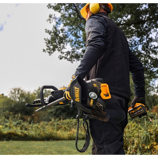 Woker carries a folded DEWALT 54V XR FLEXVOLT Split Boom with Edger Attachment
