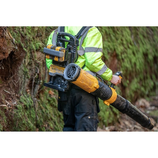 Rear view of a worker carrying a  DEWALT 2x54V Flexvolt Backpack Blower
