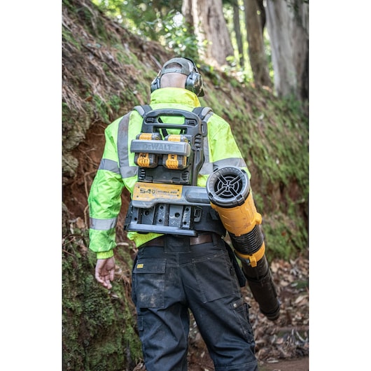 Rear view of a worker carrying a  DEWALT 2x54V Flexvolt Backpack Blower