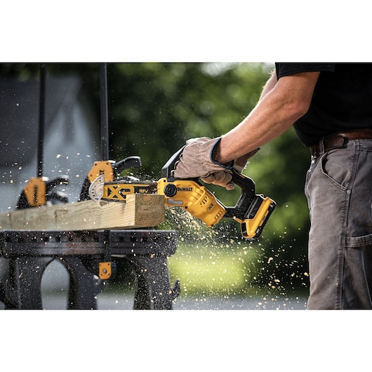 Close up of clamped lumber on a saw horse being cut with an 18V XR Brushless Chain Saw  