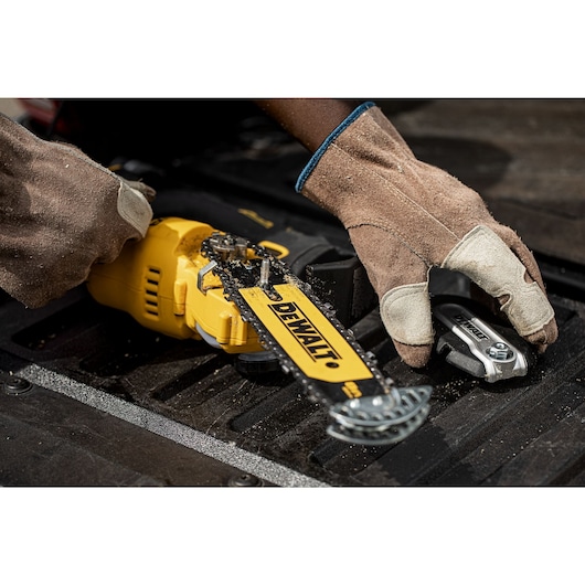 Gloved hands placing an 18V XR Brushless Chain Saw on to a black table top