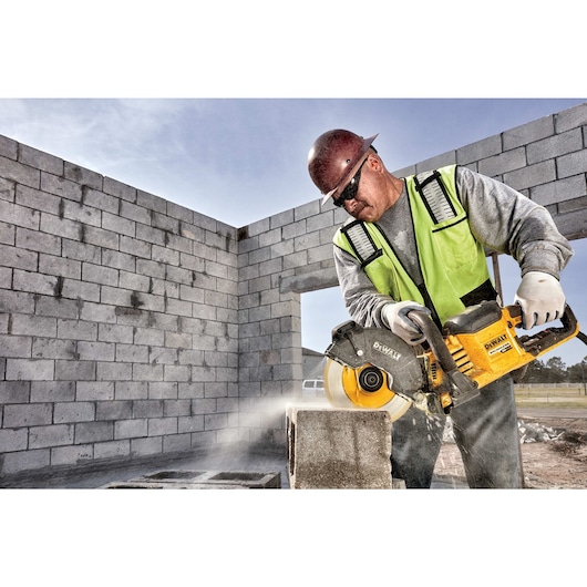 Brushless cordless cut-off saw being used by person on cinder block.