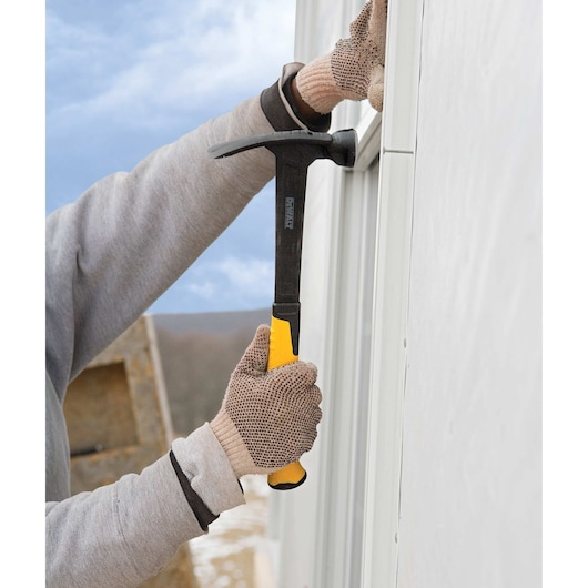 Mig weld checkered framing nailing hammer being used to hammer a nail into a wall.