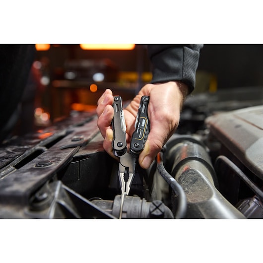 Stanley multi-tool pliers used for car engine maintenance, ideal for versatile repairs.